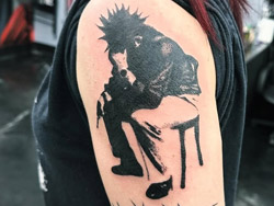 A solid, bold black ink to tattoo of a collaborative design of Sitting Stress on a client's arm, this design shows a high degree of contrast against the skin, by tattoo artist Travis Dale