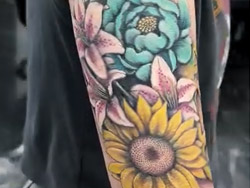 A Botanical flower motifs with intricate detailed shading an example of strong incorporation of nature-inspired floral detail performed on a client's arm by tattoo artist Travis Dale