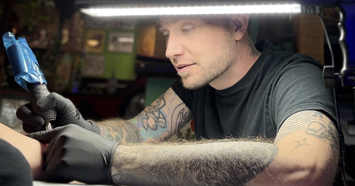 Travis at the shop tattooing a client.