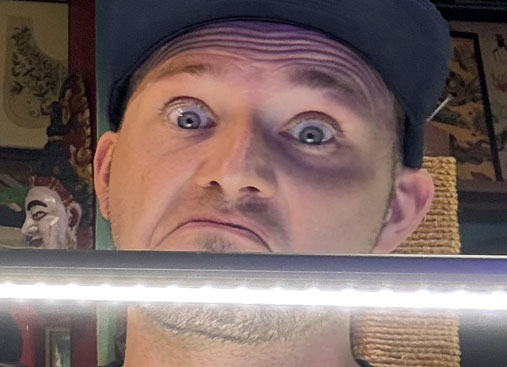 Travis' surprised expression, his eyes wide and eyebrows raised high.