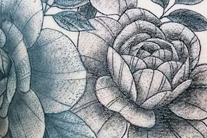 The image shows a detailed black and grey floral tattoo on a person's skin, featuring roses and other flowers.
